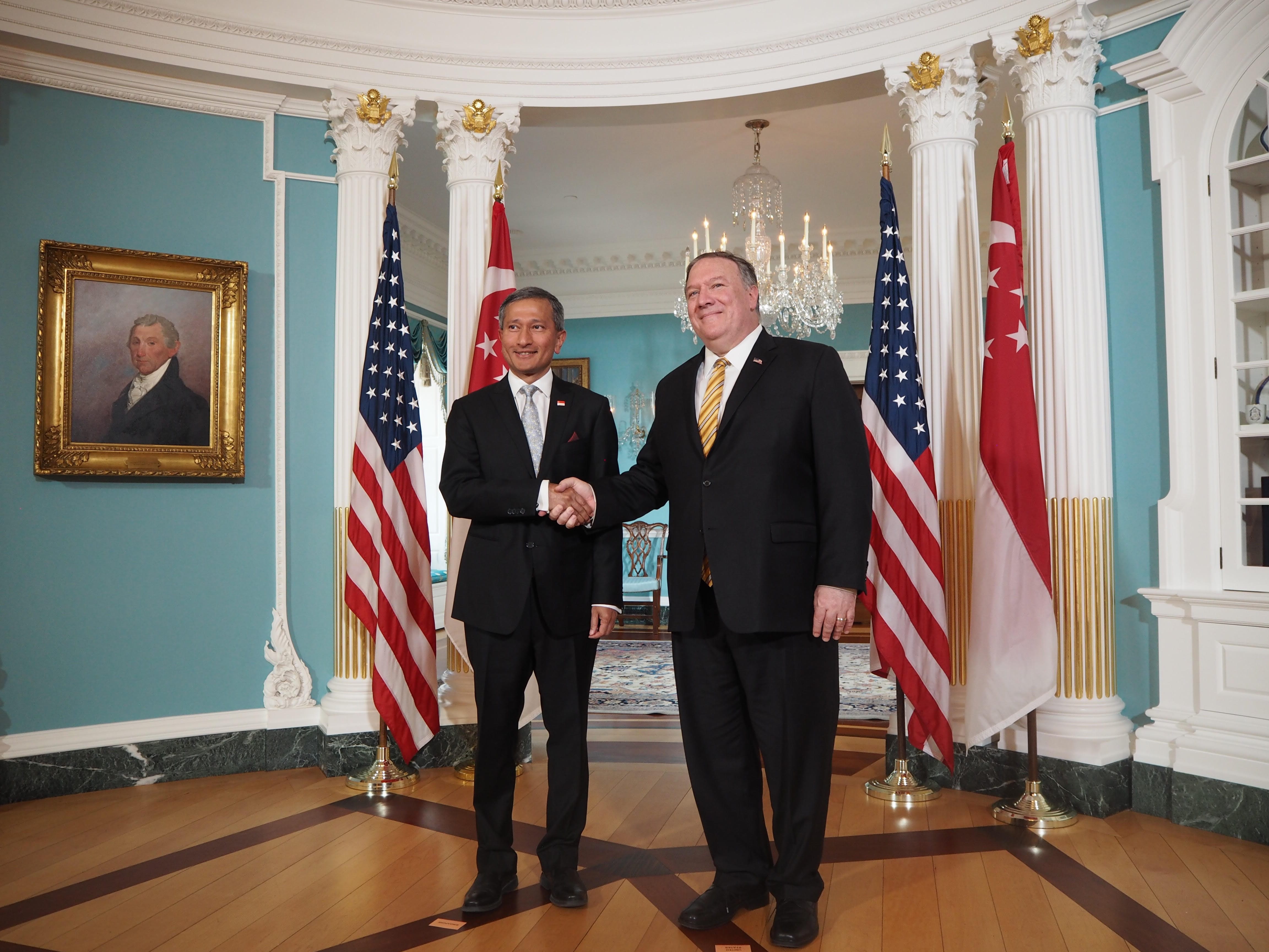 Mike Pompeo & Vivian Balakrishnan shake hands between US and Singapore flags.